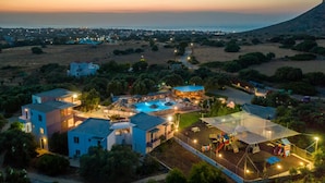 An aerial view of a resort with multiple buildings, a swimming pool, and a large covered area with play equipment. - Paradisio Baby and Kinder Hotel (Chania)