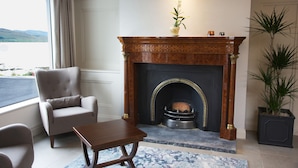 Una habitación con chimenea, una silla, una mesa y vistas al exterior.