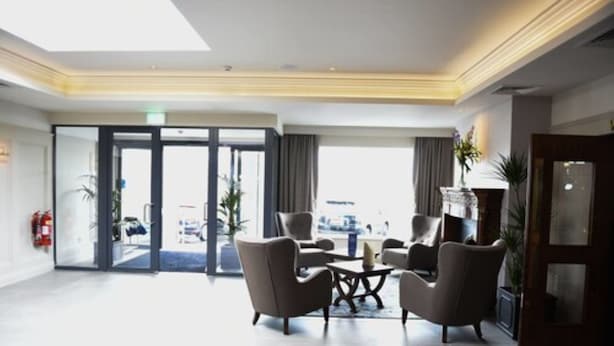 Un vestíbulo de hotel con zona de estar, mostrador de recepción y vista a la calle.
