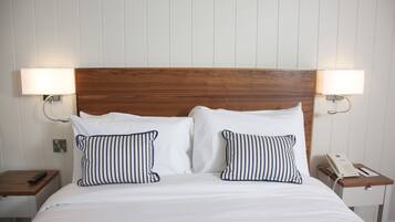 Restful retreat with a neatly made bed, two wall-mounted lamps, and a wooden nightstand.
