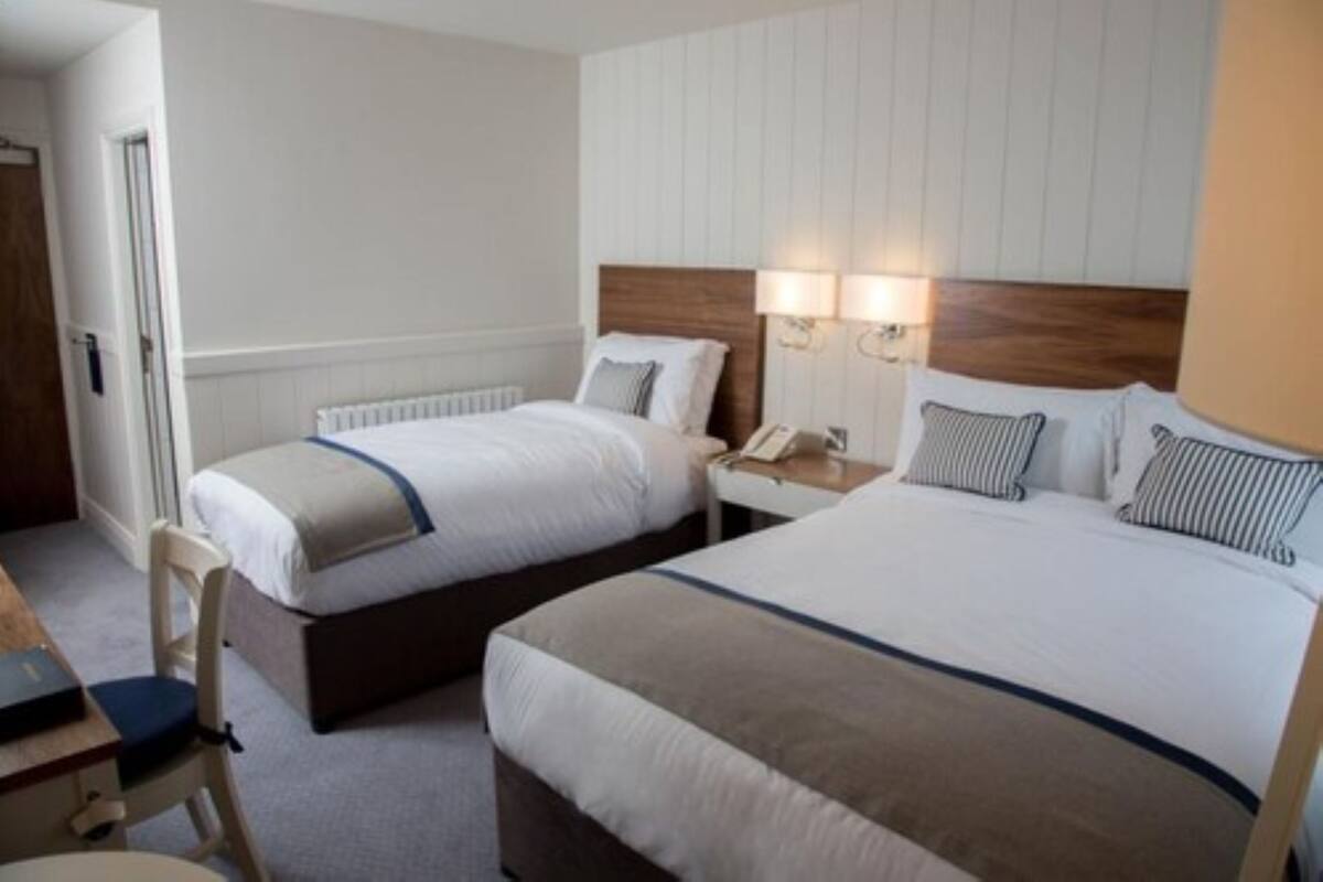 A hotel room with two single beds, a wooden headboard, bedside lamps, a telephone, and a chair.