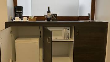 A kitchenette with a microwave, coffee maker, and wine bottle.