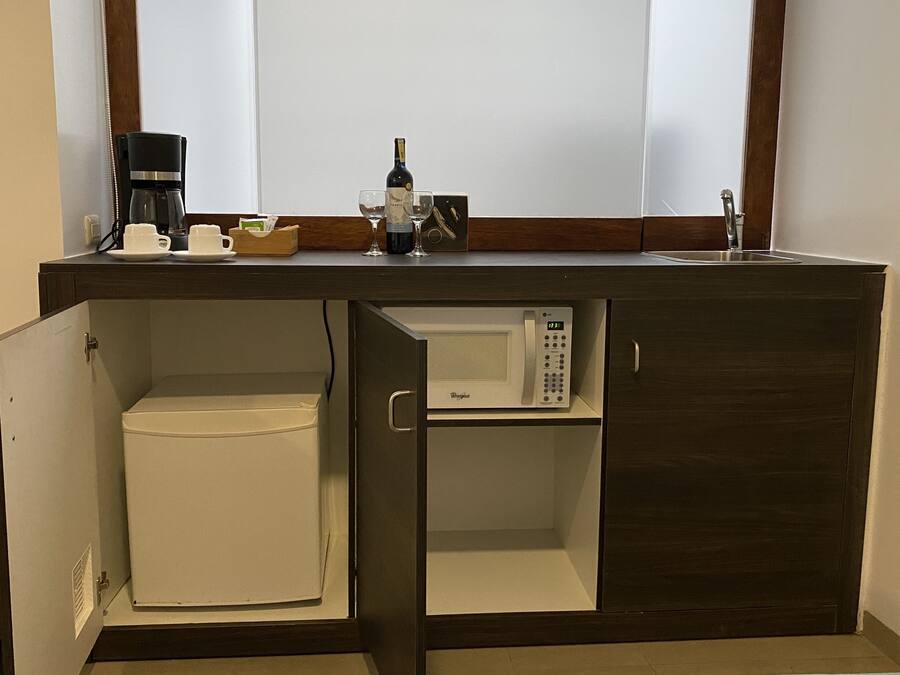 A kitchenette with a microwave, coffee maker, and wine bottle.