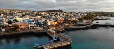 A coastal town with a pier, buildings, and a rocky shoreline.
