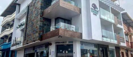 Un edificio moderno de varios pisos con un espacio comercial en la planta baja, balcones y un letrero visible para un negocio llamado 'MINIMARKET'.