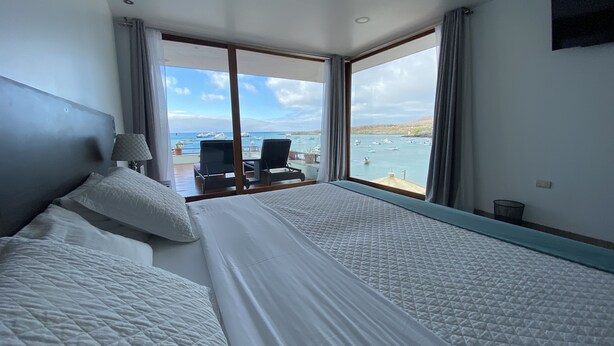 Ein Hotelzimmer mit einem großen Bett, einem Schreibtisch und Blick aufs Meer.