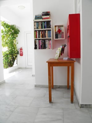 A hallway with a bookshelf, a red cabinet, and a fire extinguisher. - Christi Apartments (Apokoronas)