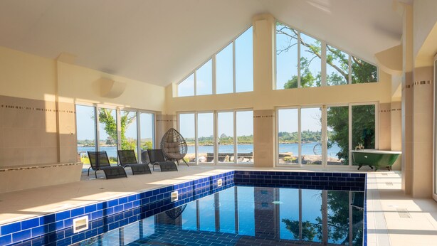 Une piscine intérieure moderne dotée de grandes baies vitrées offrant une vue sur la mer.