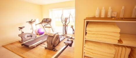 A home gym with exercise equipment, a yoga mat, and a shelf with towels.