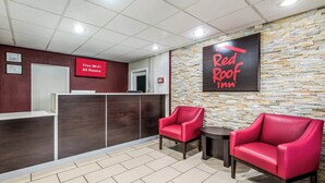 A reception area with a Red Roof Inn sign, a 'Free Wi-Fi All Rooms' notice, and two red chairs. - Red Roof Inn & Suites Wapakoneta (Wapakoneta)