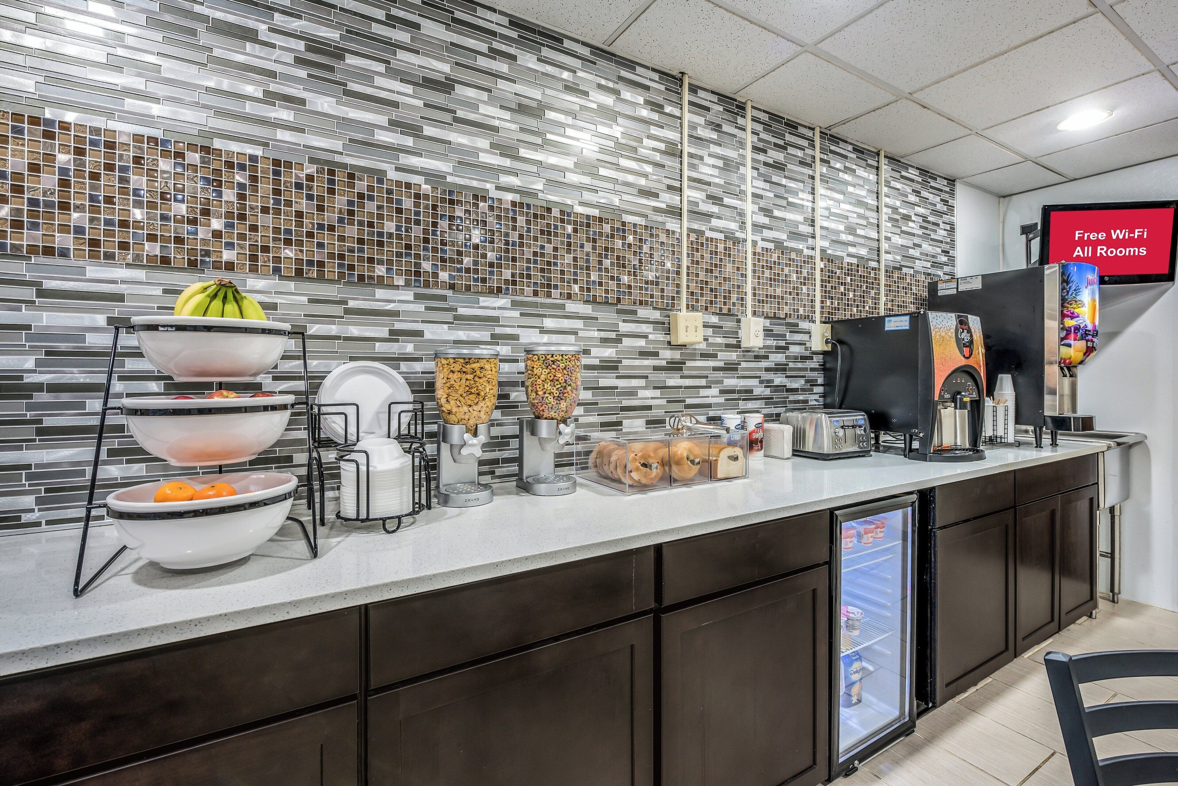 Un espace cuisine moderne doté d’un bar pour prendre le petit-déjeuner, de distributeurs de céréales en libre-service, d’une machine à café et d’un réfrigérateur.