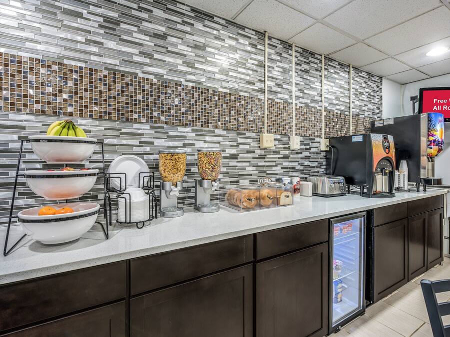 A modern kitchen area with a breakfast bar, self-serve cereal dispensers, a coffee machine, and a refrigerator.