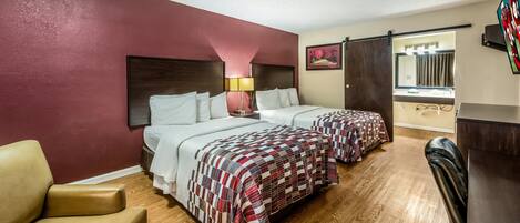 A hotel room with two beds, a desk, a chair, and a TV.