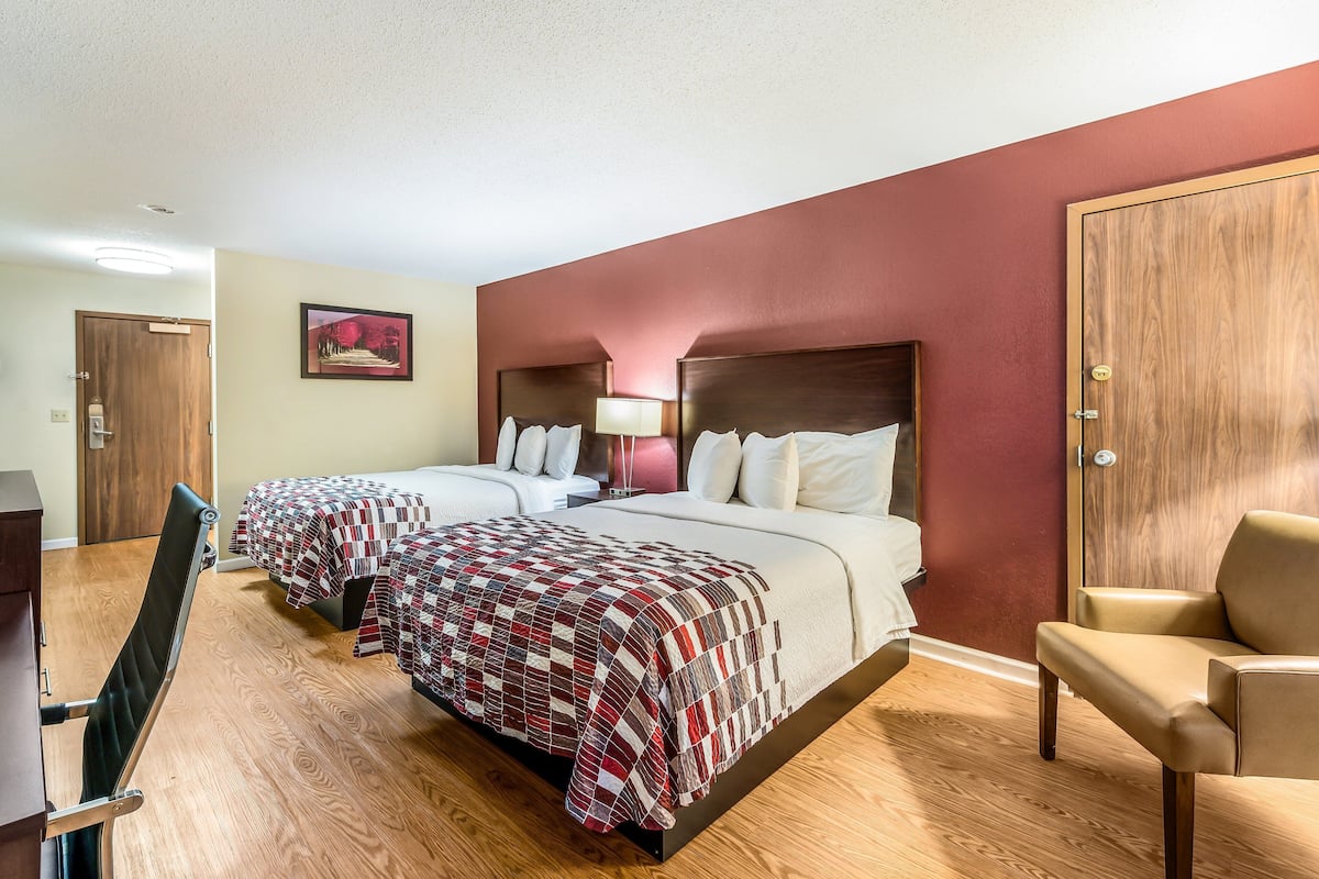 Een hotelkamer met twee bedden, een bureau en een stoel.