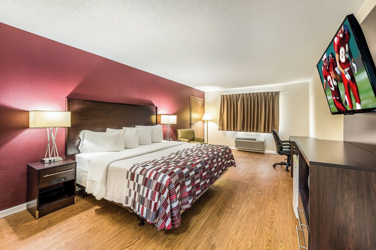 A hotel room with a bed, bedside tables, a TV, and a desk.