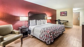 Ein Hotelzimmer mit Bett, Nachttischen, Schreibtisch, Stuhl und einer Tür.
