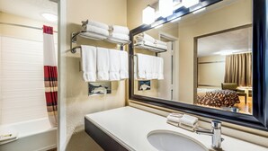 A hotel bathroom with a large mirror, a sink, and a towel rack. - Red Roof Inn & Suites Wapakoneta (Wapakoneta)