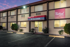 Ein Red Roof Inn & Suites Hotel mit einem 'WELCOME'-Schild, mehreren Fenstern und einem Parkplatz.