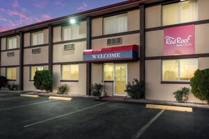 Un Red Roof Inn & Suites con un letrero que dice 'WELCOME', varias ventanas y un estacionamiento.