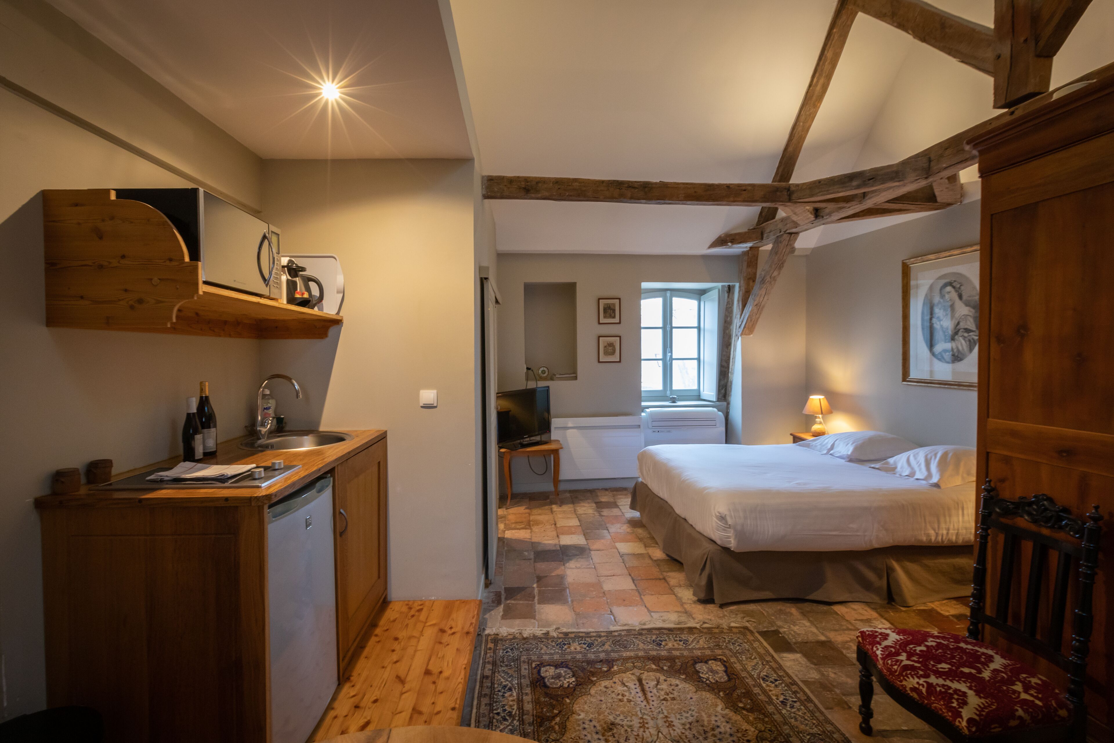 A cozy bedroom with a wooden ceiling, a bed, a nightstand, and a window.