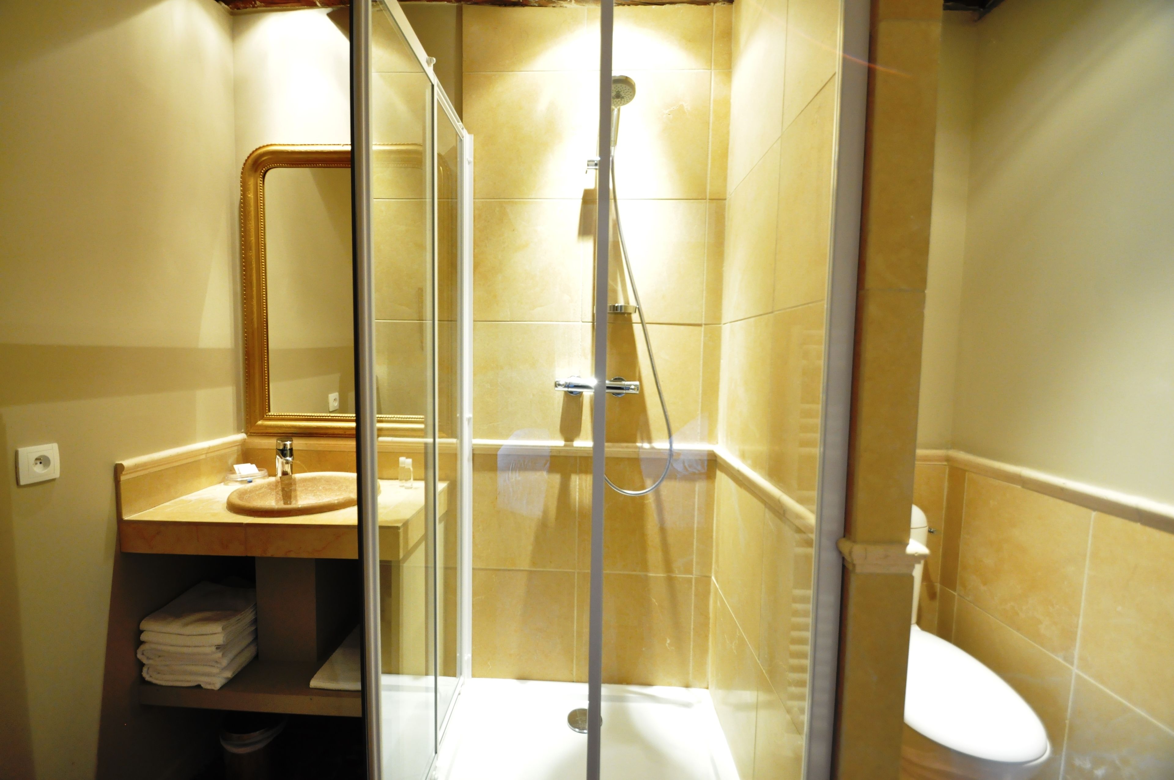 A bathroom with a glass-enclosed shower, a sink with a mirror, and a toilet.