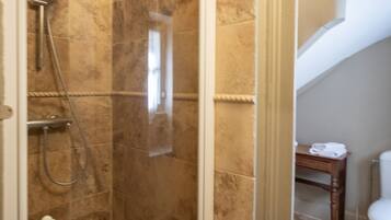 A bathroom with a shower area, a toilet, and a small table with towels.