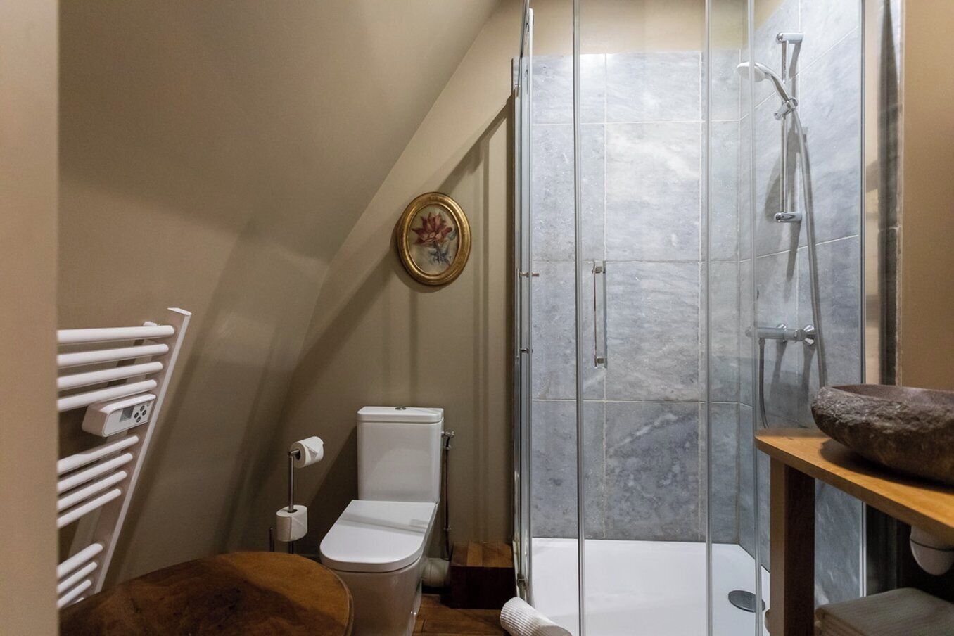 A modern bathroom with a toilet, shower, and a wooden vanity.