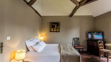 A bedroom with a bed, bedside lamp, TV, and a chair.