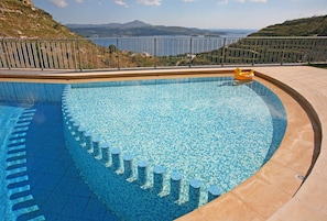 Une piscine avec vue sur la mer et les montagnes.