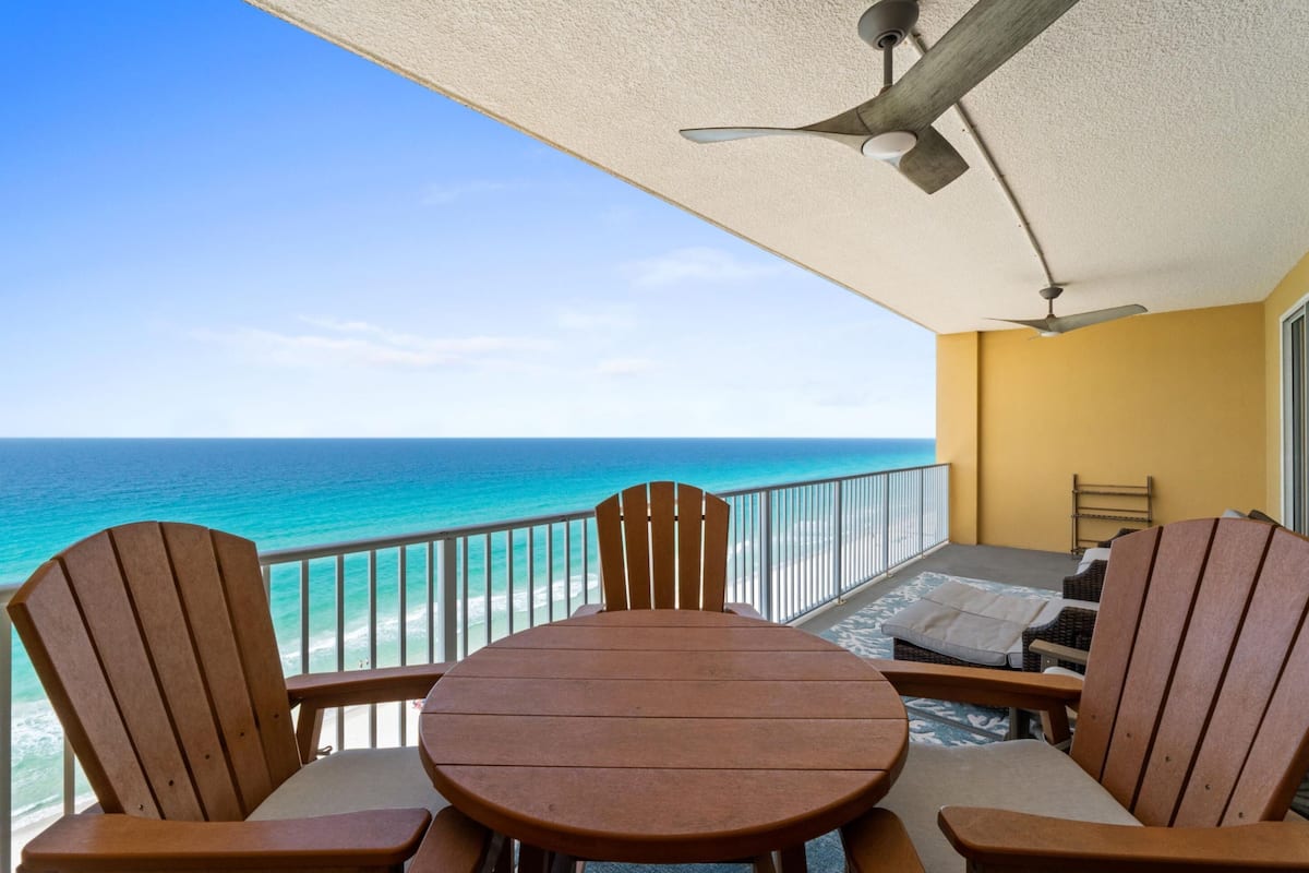 A balcony with a table and chairs, a ceiling fan, and a view of the ocean.