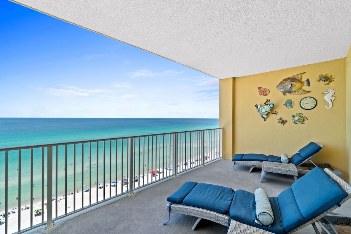 A balcony with wicker lounge chairs and a view of the beach.