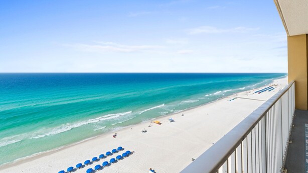 A beach view from a balcony with a railing, a sandy beach, and a clear sky. - Tropic Winds by Panhandle Getaways (Panama City Beach)