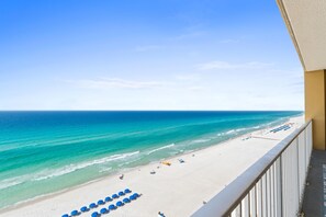 A beach view from a balcony with a railing, a sandy beach, and a clear sky. - Tropic Winds by Panhandle Getaways (Panama City Beach)