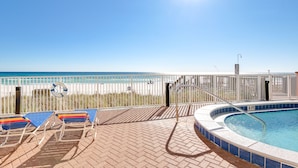 A pool area with a view of the beach, lounge chairs, and a lifeguard stand. - Tropic Winds by Panhandle Getaways (Panama City Beach)