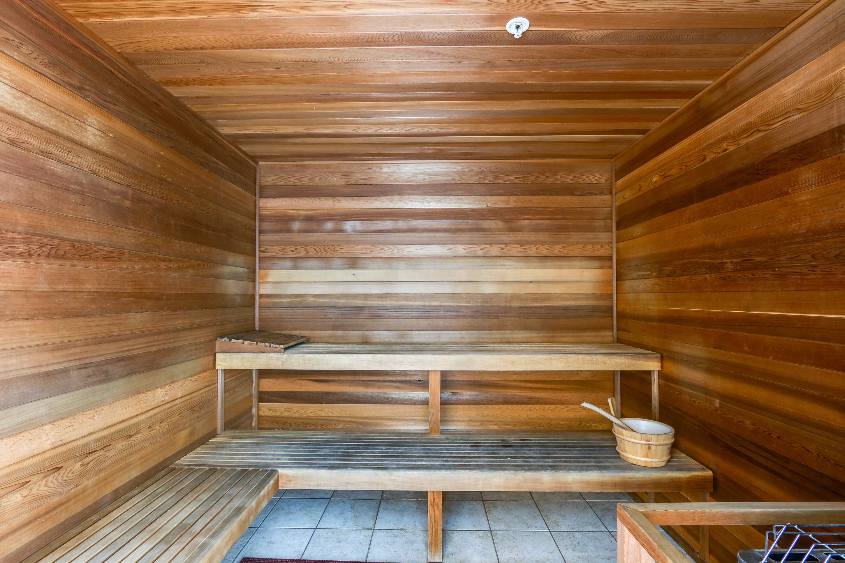 A sauna with wooden benches and a wooden table with a bucket.