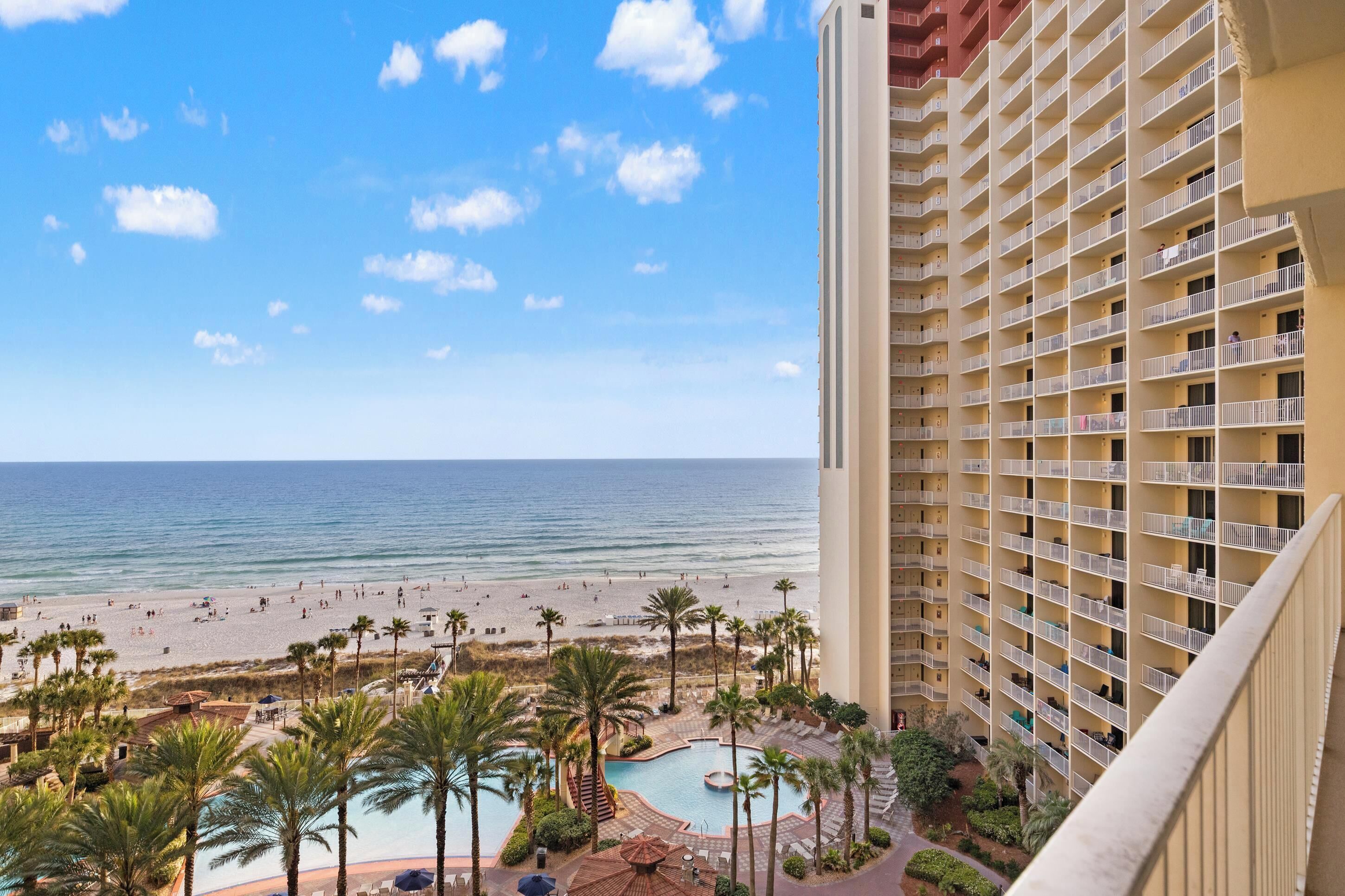 A high-rise hotel with a pool area, beach view, and multiple balconies.