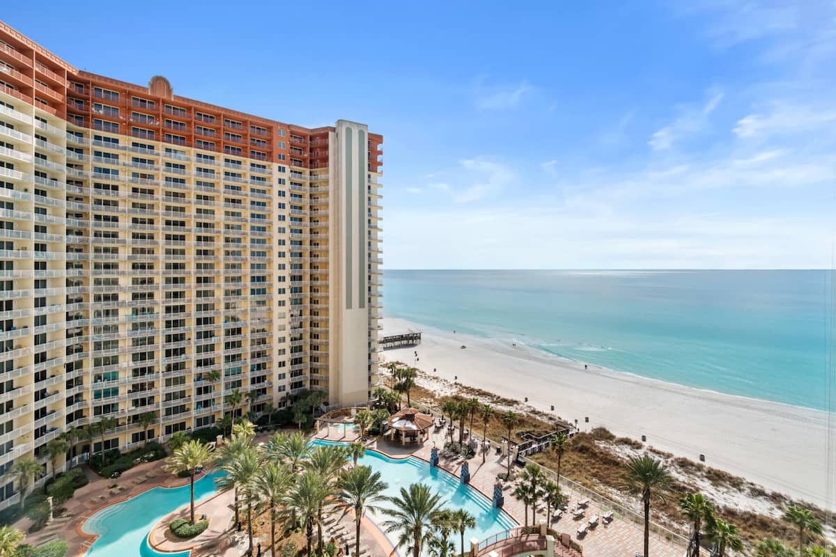 A high-rise hotel with a pool area and beach view.
