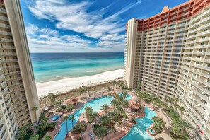 Un hotel con zona de piscina, vistas a la playa y varios balcones.