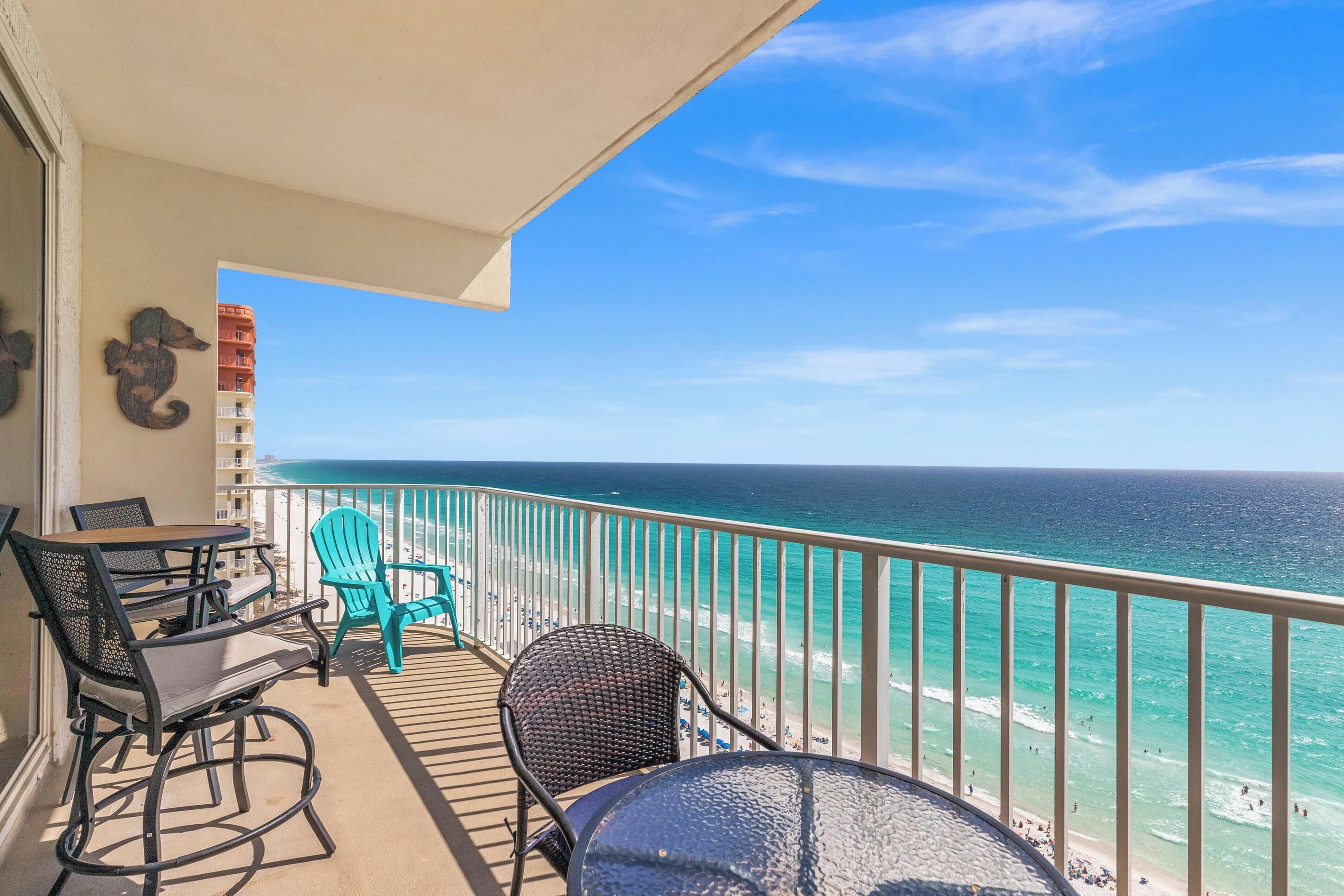 A balcony with outdoor furniture, a seahorse decoration, and a view of the ocean.