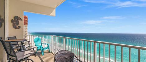 A balcony with outdoor furniture, a seahorse decoration, and a view of the ocean.