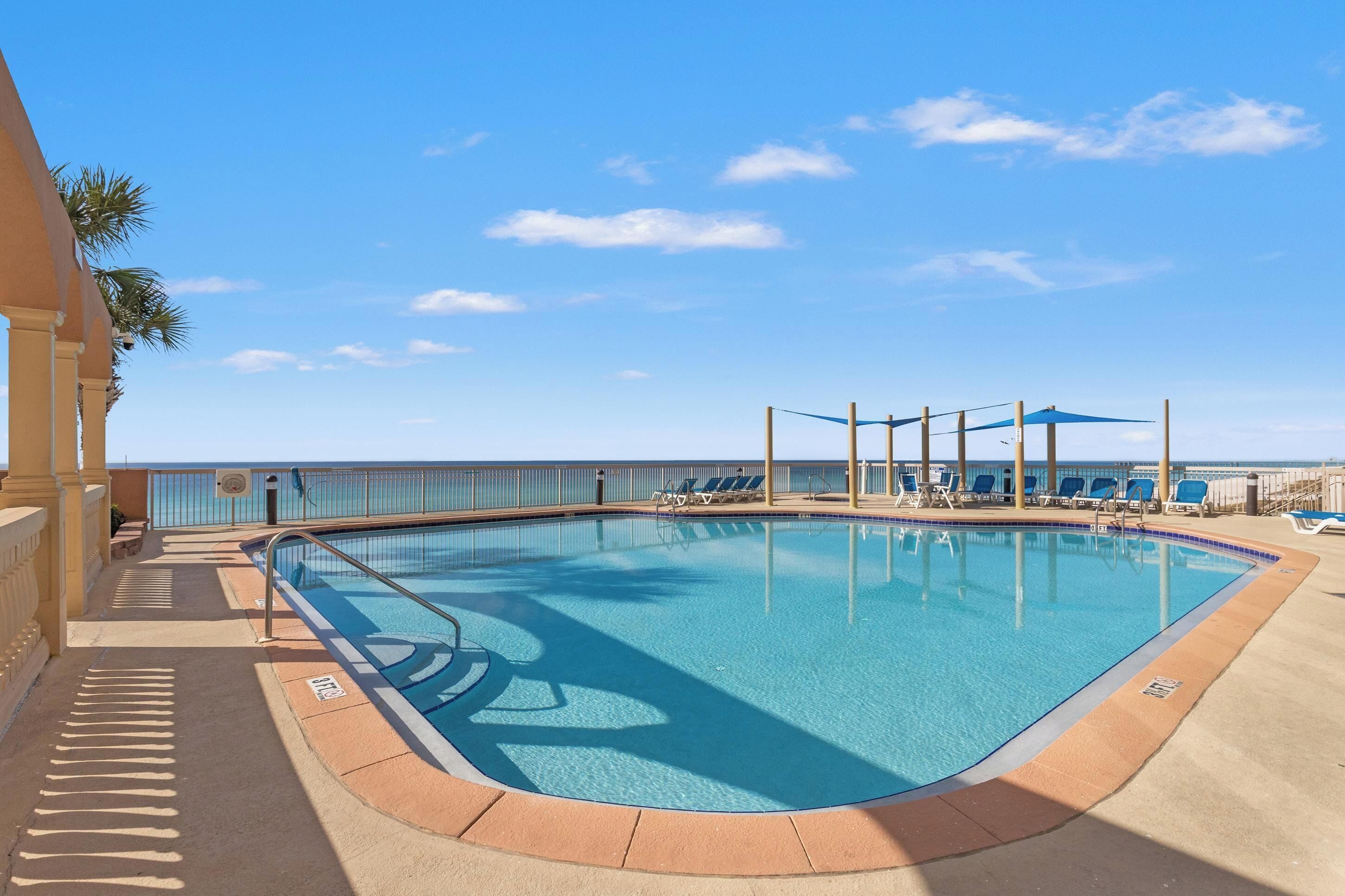 A pool with a clear blue sky and a view of the ocean.