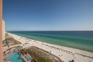 A beach resort with a swimming pool, beach chairs, and a view of the ocean. - Sunrise Beach Resort by Panhandle Getaways (Panama City Beach)