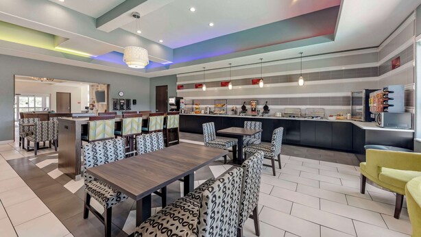 A modern restaurant with a bar area, seating with patterned upholstery, and a tiled floor. - Best Western Plus Pflugerville (Pflugerville)