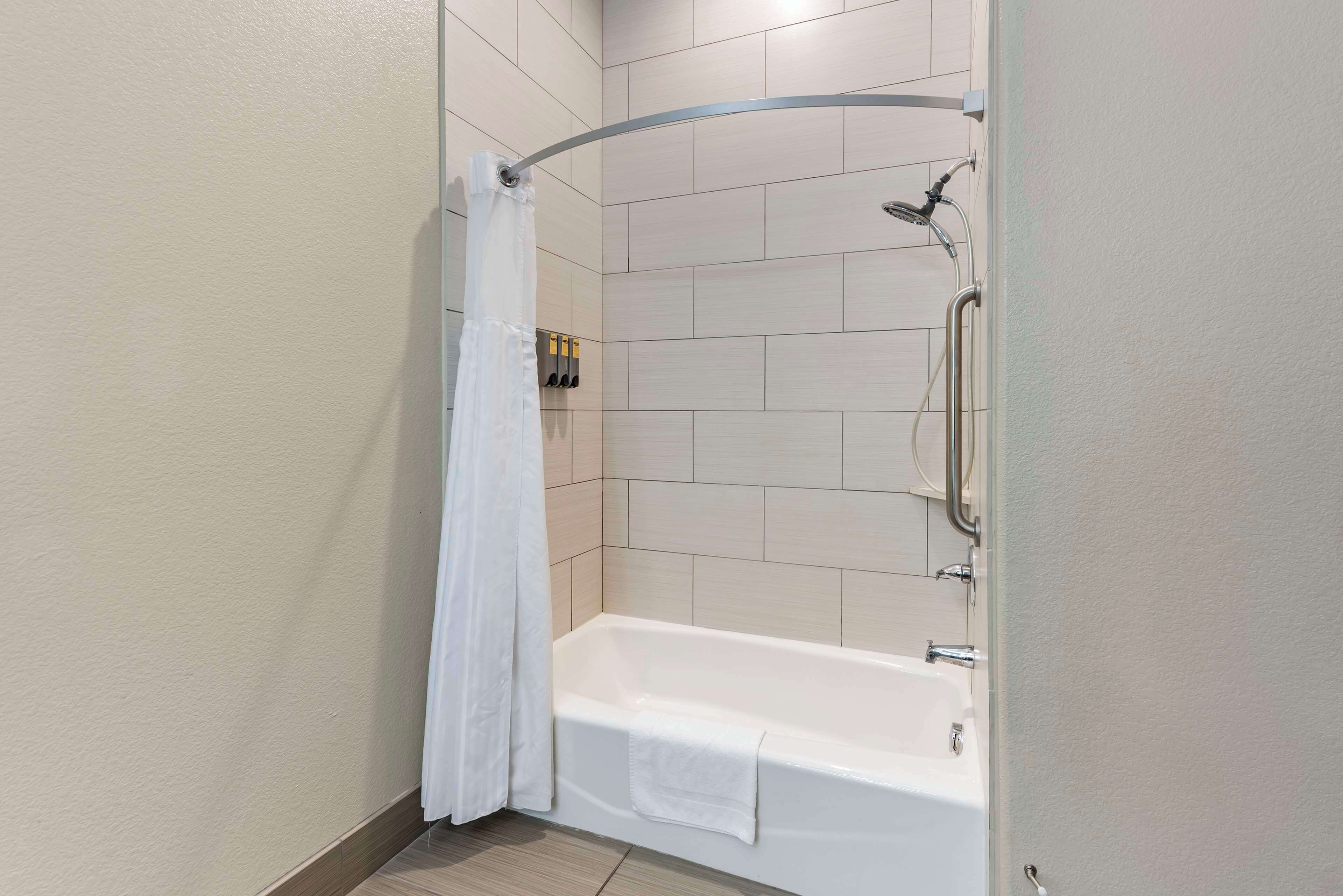 Un baño moderno con bañera, ducha y una cortina blanca.