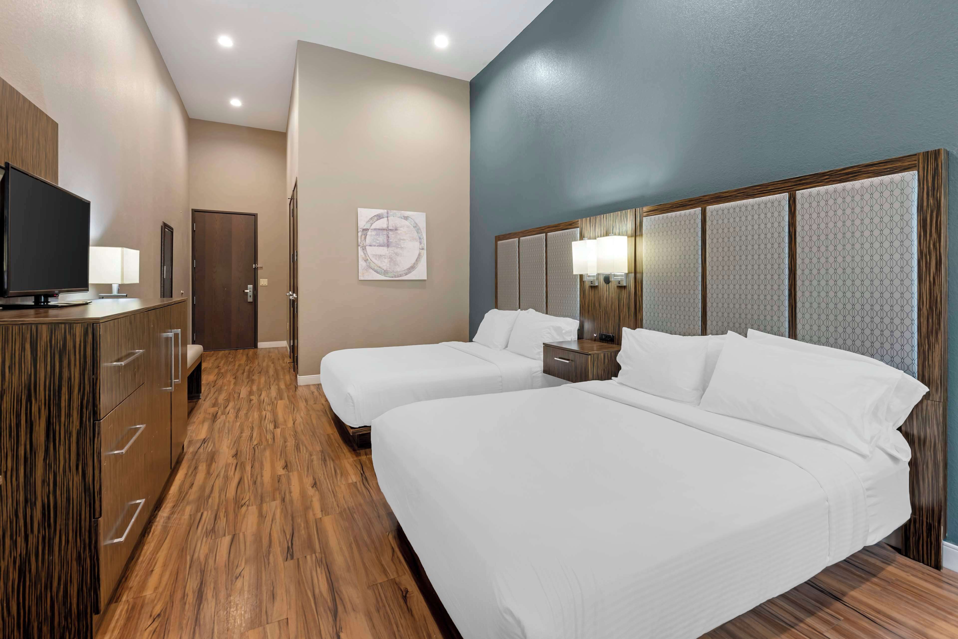 A hotel room with two beds, a TV, a desk, and a wardrobe.
