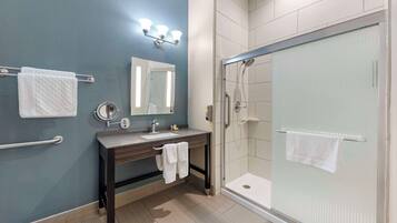 A bathroom with a sink, mirror, towel rack, and a walk-in shower.