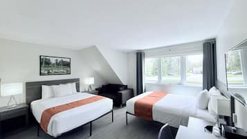 A hotel room with two beds, a desk, a chair, a window with curtains, and a painting on the wall.