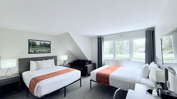 Habitación de hotel con dos camas, un escritorio, una silla, una ventana con cortinas y un cuadro en la pared.