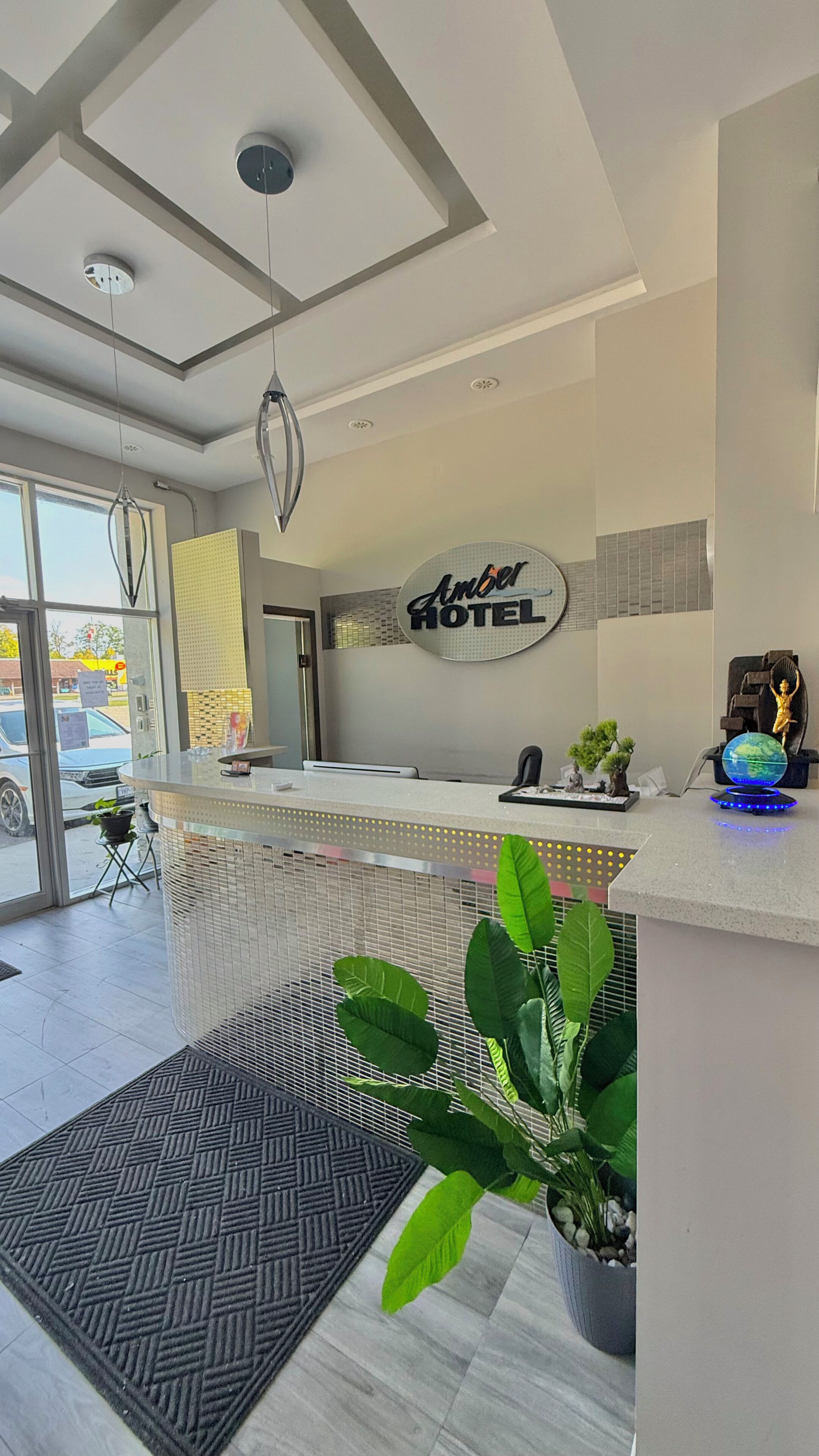 A hotel reception area with a modern design, including a reception desk, a globe, and a statue.