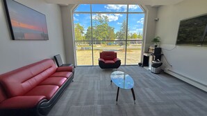 A modern waiting area with a red leather couch, a glass table, and a red chair. - Amber Hotel (Lambton Shores)